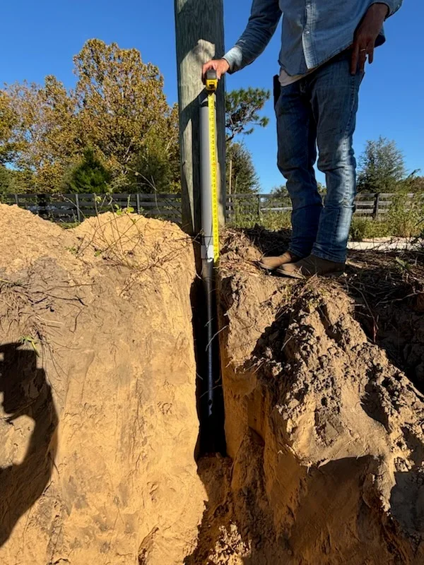 Wooden fence post removal from trench with tape measure, hand tools, excavated soil