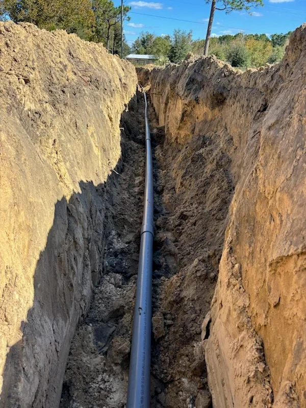 Deep utility trench with vertical soil walls and installed PVC pipe for underground infrastructure