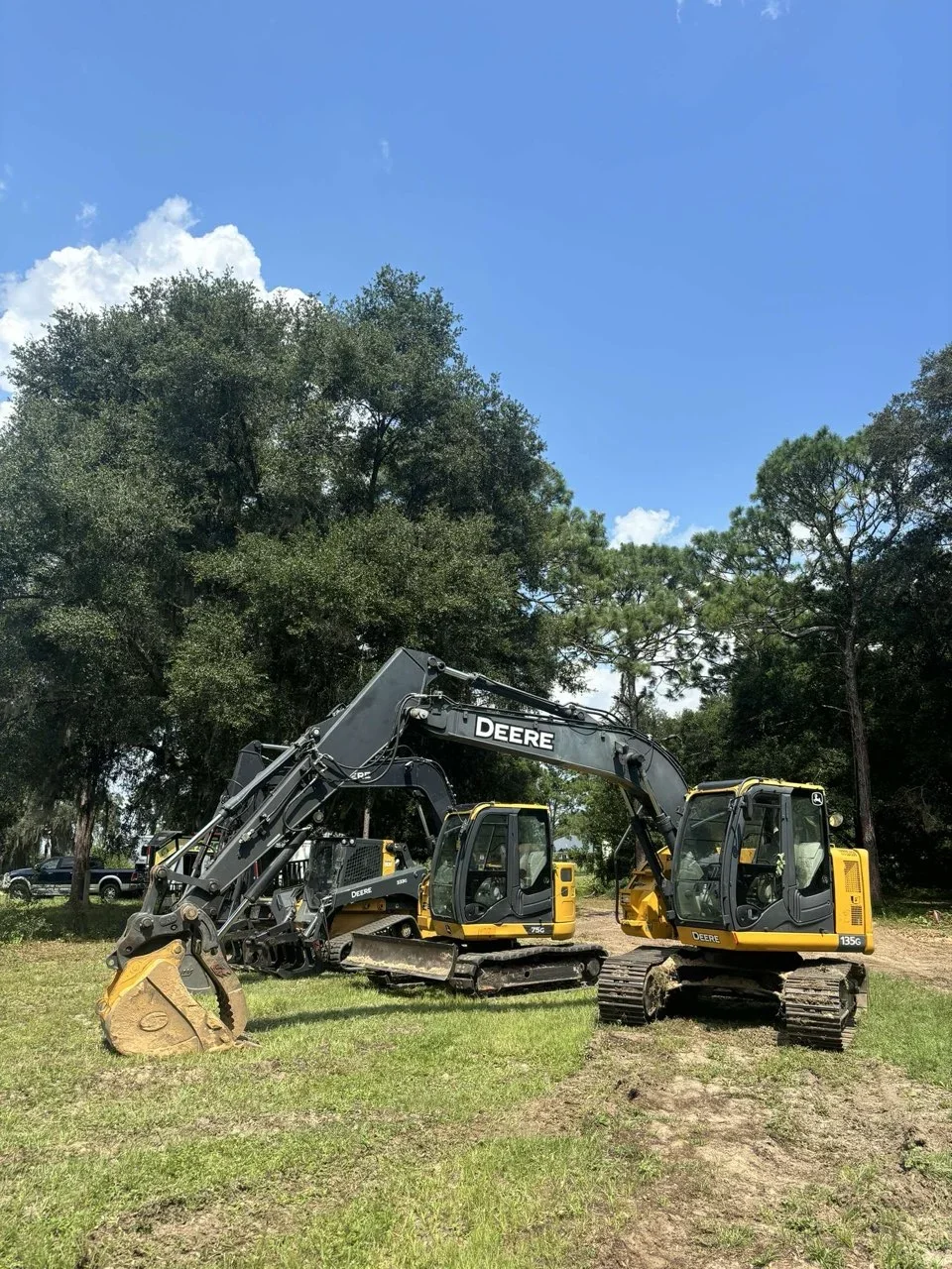 John Deere excavators with grapple bucket clearing trees and land